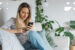 Young woman scrolling on her mobile device in a living room.