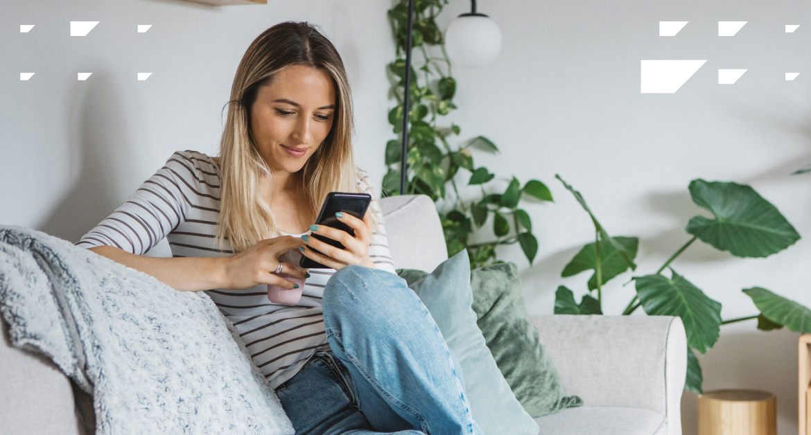 Young woman scrolling on her mobile device in a living room.