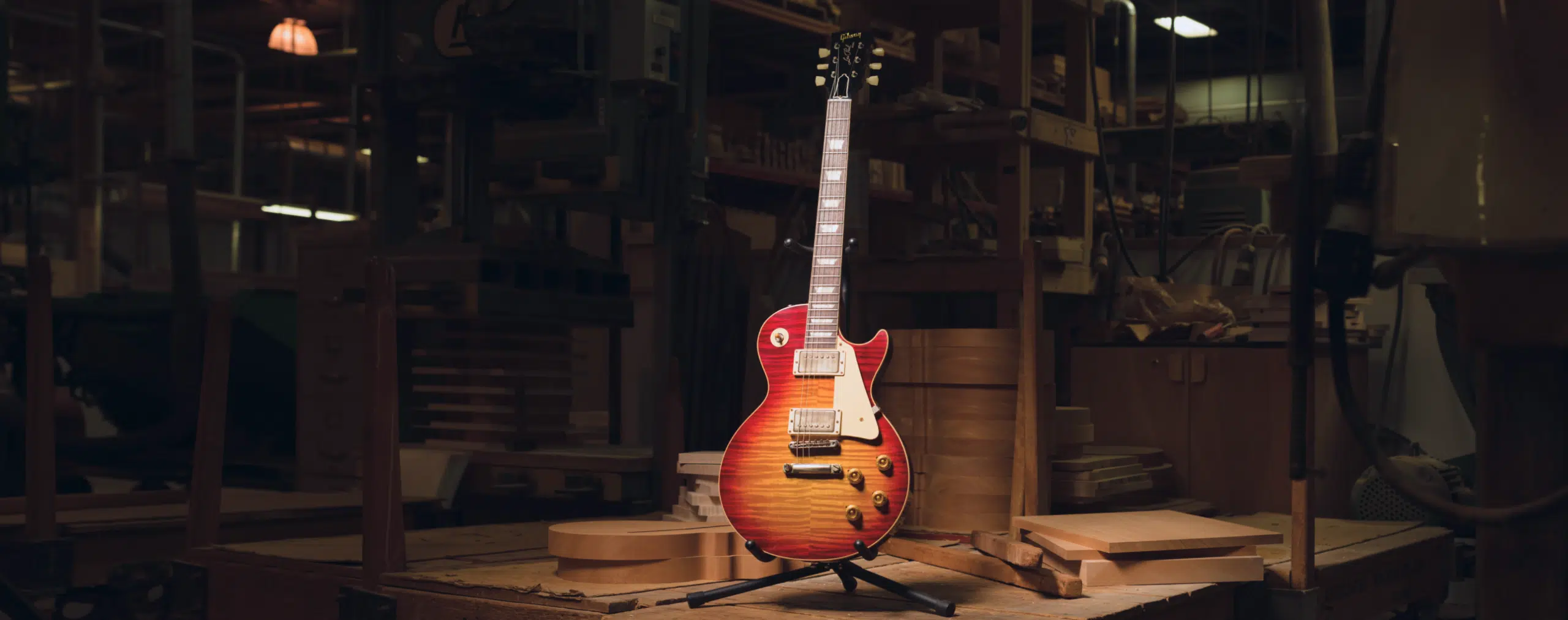 Electric guitar on a stand in a woodwork shop surrounded by tools and wood pieces.