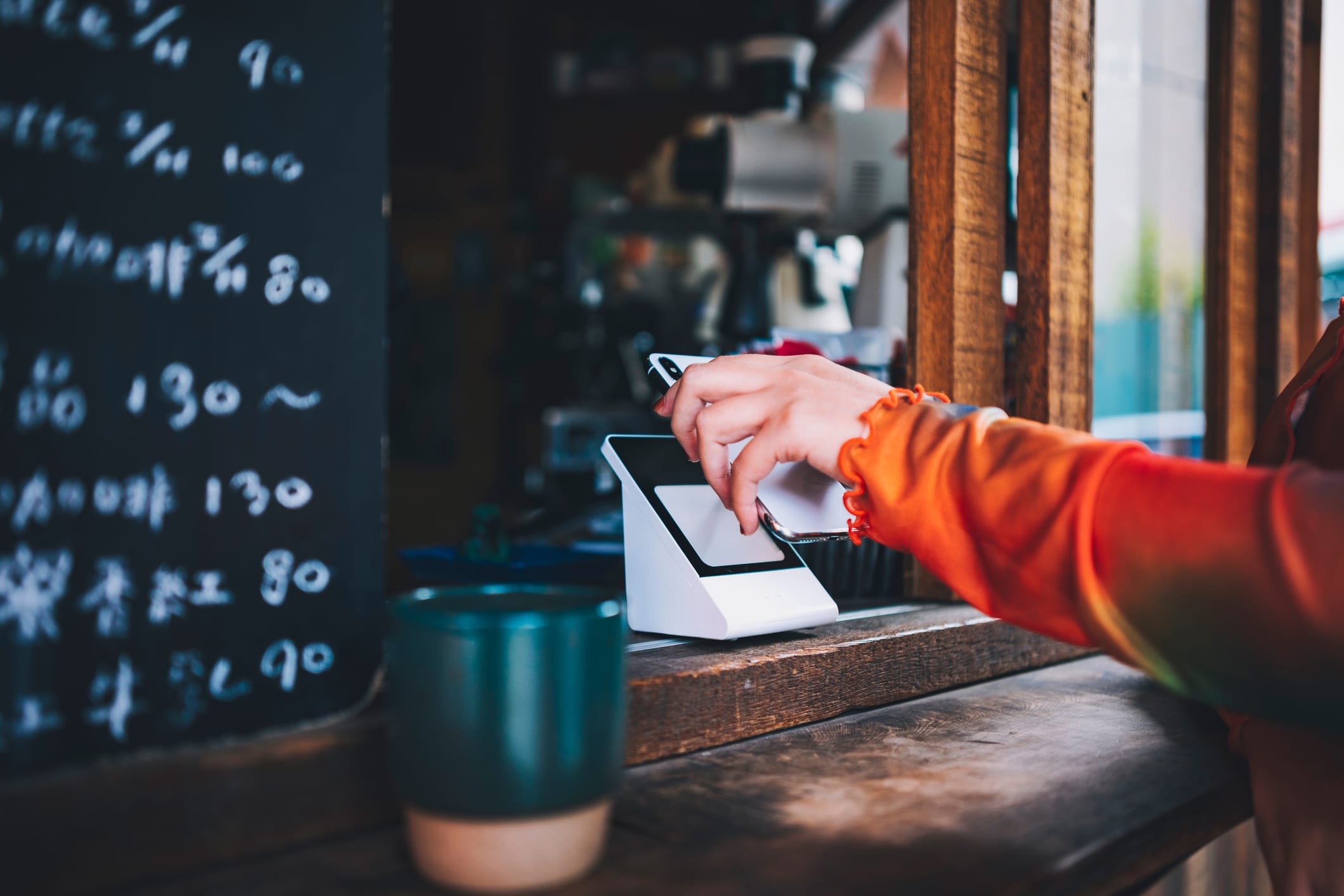 A Woman Uses Her Smartphone To Make A Payment With The Cashier. She Scans The Qr Code Using A Card Reader To Complete A Convenient Contactless Payment.