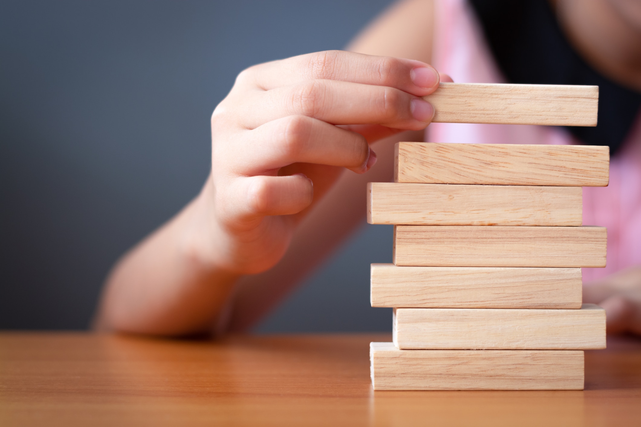 Girl's Hand Stacking Wooden Blocks.