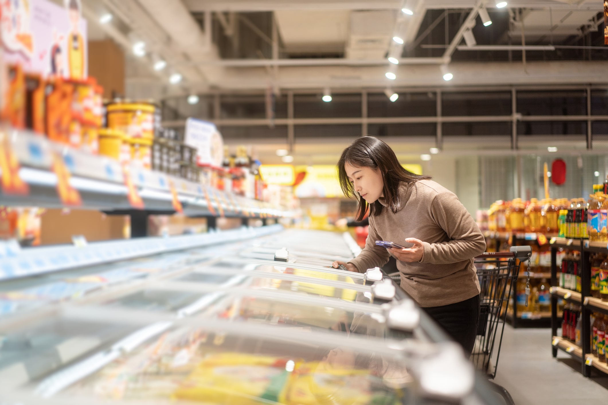 Asian Women Are Choosing Frozen Foods In The Supermarket.