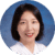 A person smiling wearing a white shirt against a blue background.