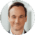 A person is smiling in a headshot photograph with a blurred neutral background.