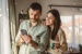 Young heterosexual couple in their 20s-30s looking at a phone together in their home.