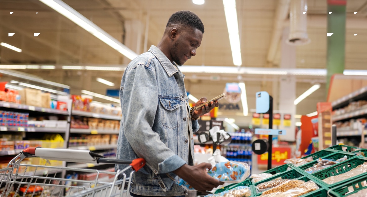 young male in a grocery store using phone to decide on a purchase