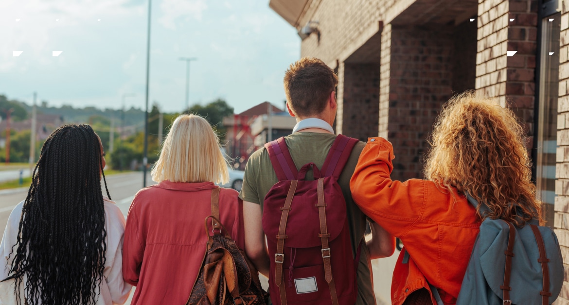 Four teenager friends with school bags walking together.