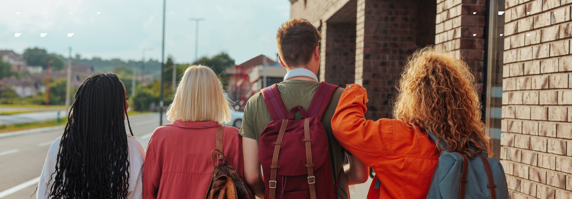 Four teenager friends with school bags walking together.