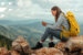 30-something female hiker sitting on top of a mountain looking at her phone