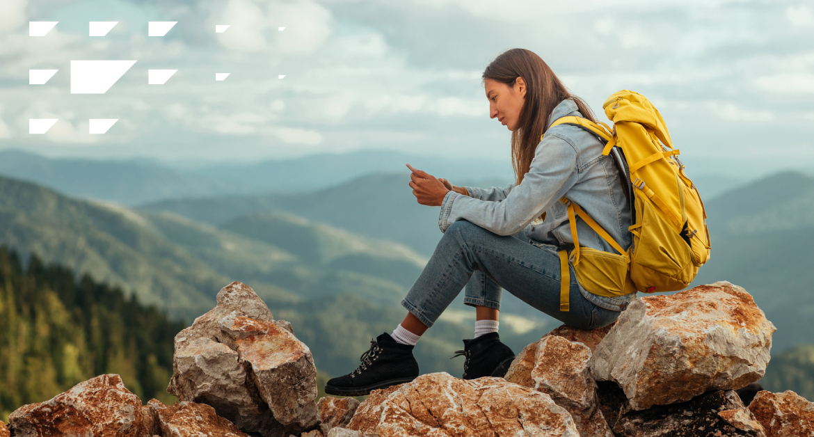 30-something female hiker sitting on top of a mountain looking at her phone