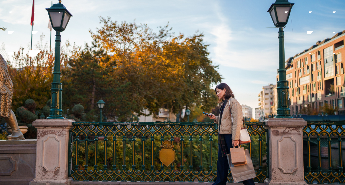 Shopper walking through autumnal street on her phone.