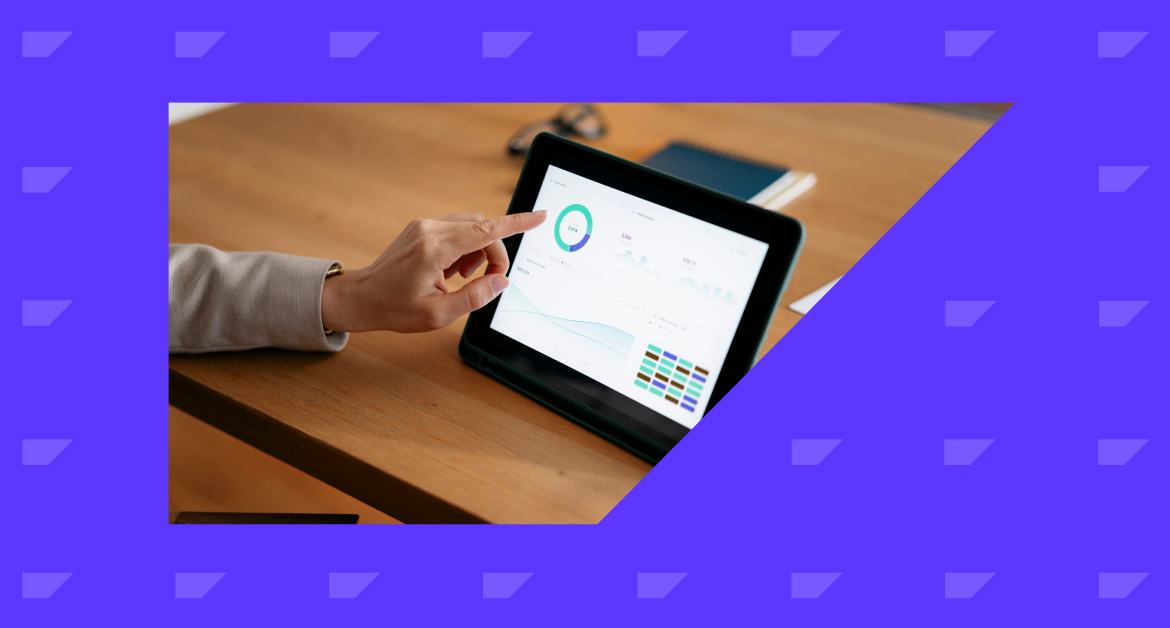 Marketer tapping a tablet screen on a desk showing a marketing automation workflow.