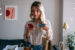 Young woman in her 20s using her credit card to buy something on her phone.