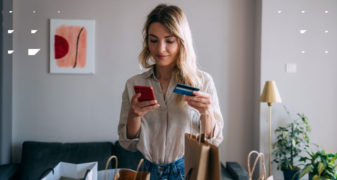 Young woman in her 20s using her credit card to buy something on her phone.