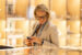 Woman in her 50s in a premium retail environment looking at a laptop while holding her phone.