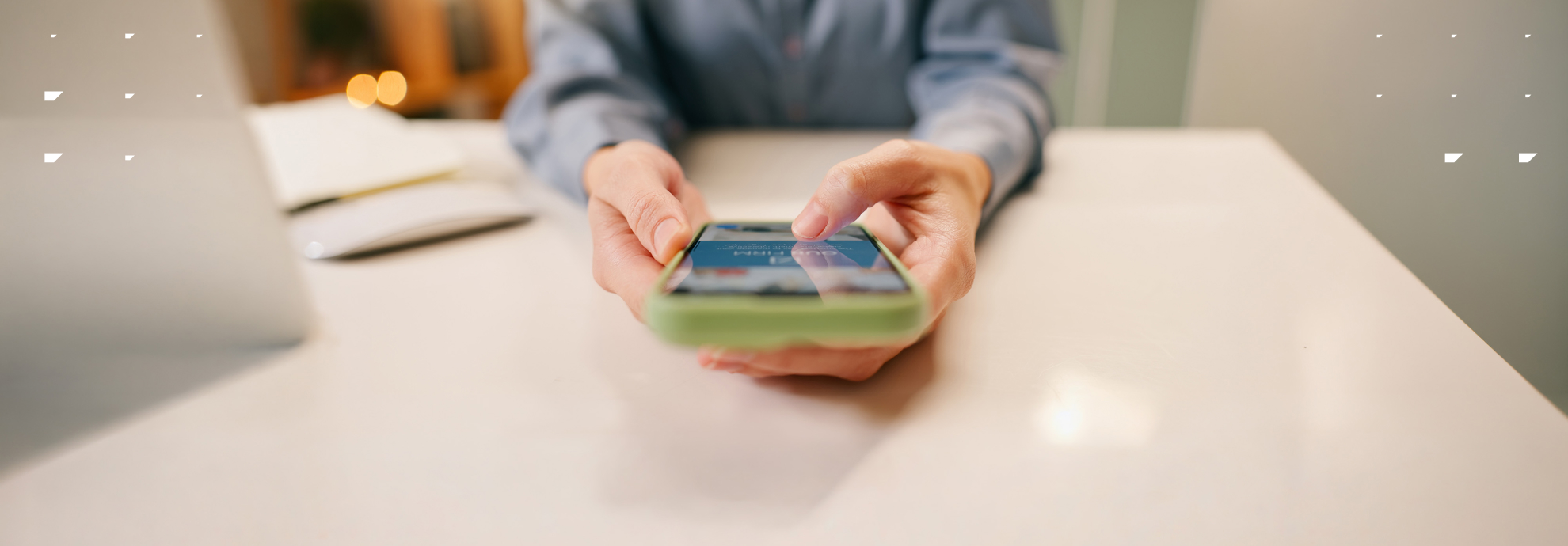 Marketer using a phone and laptop at a desk.
